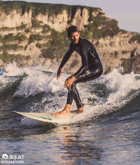 Mann in Neoprenanzug surft gebrochene Welle auf weißem Surfboard im Surfcamp Spanien Liquid Surf House Spanien Bucht von Langre