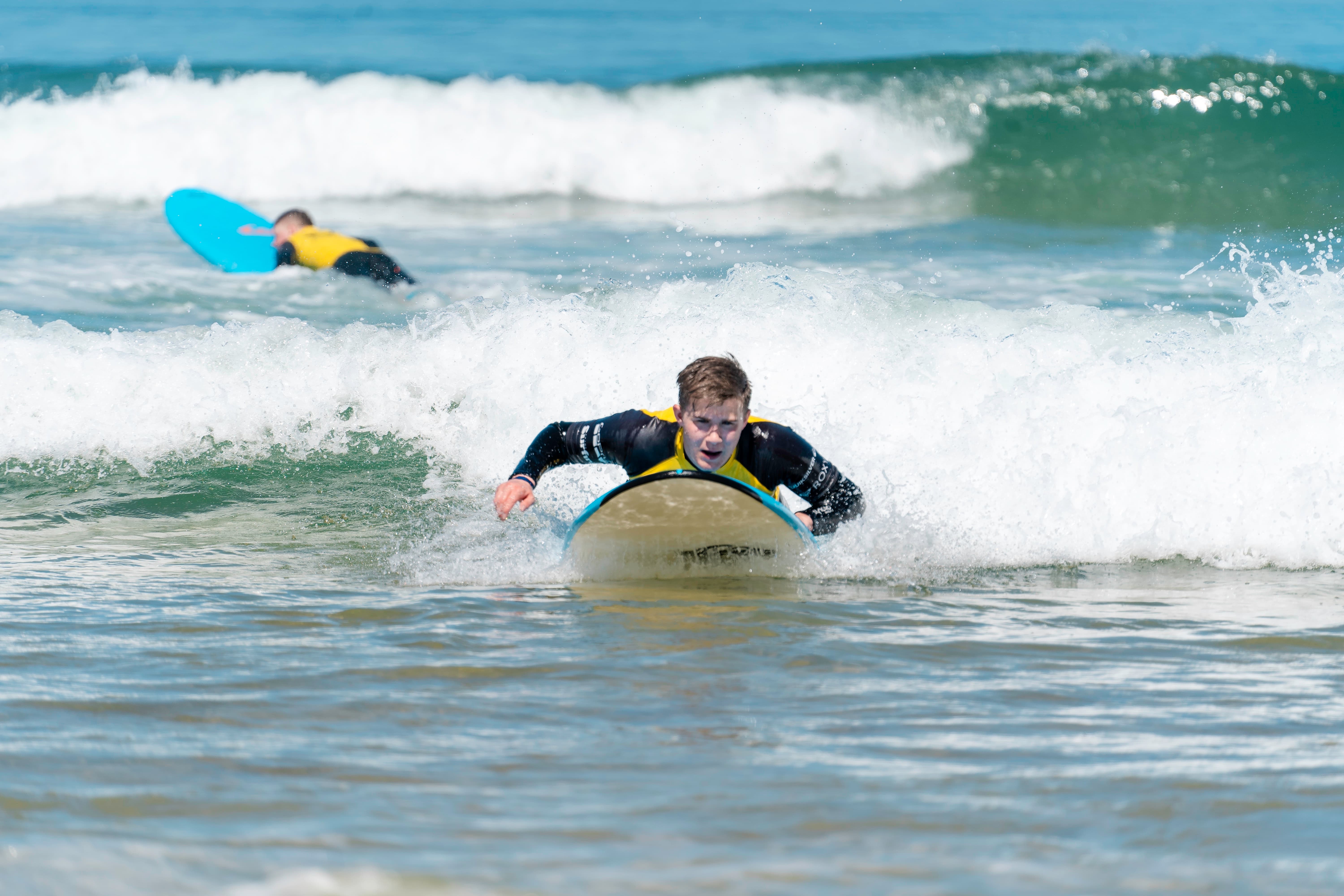 Erste Paddelzüge Ein Junge paddelt auf seinem Surfbrett durchs Weisswasser