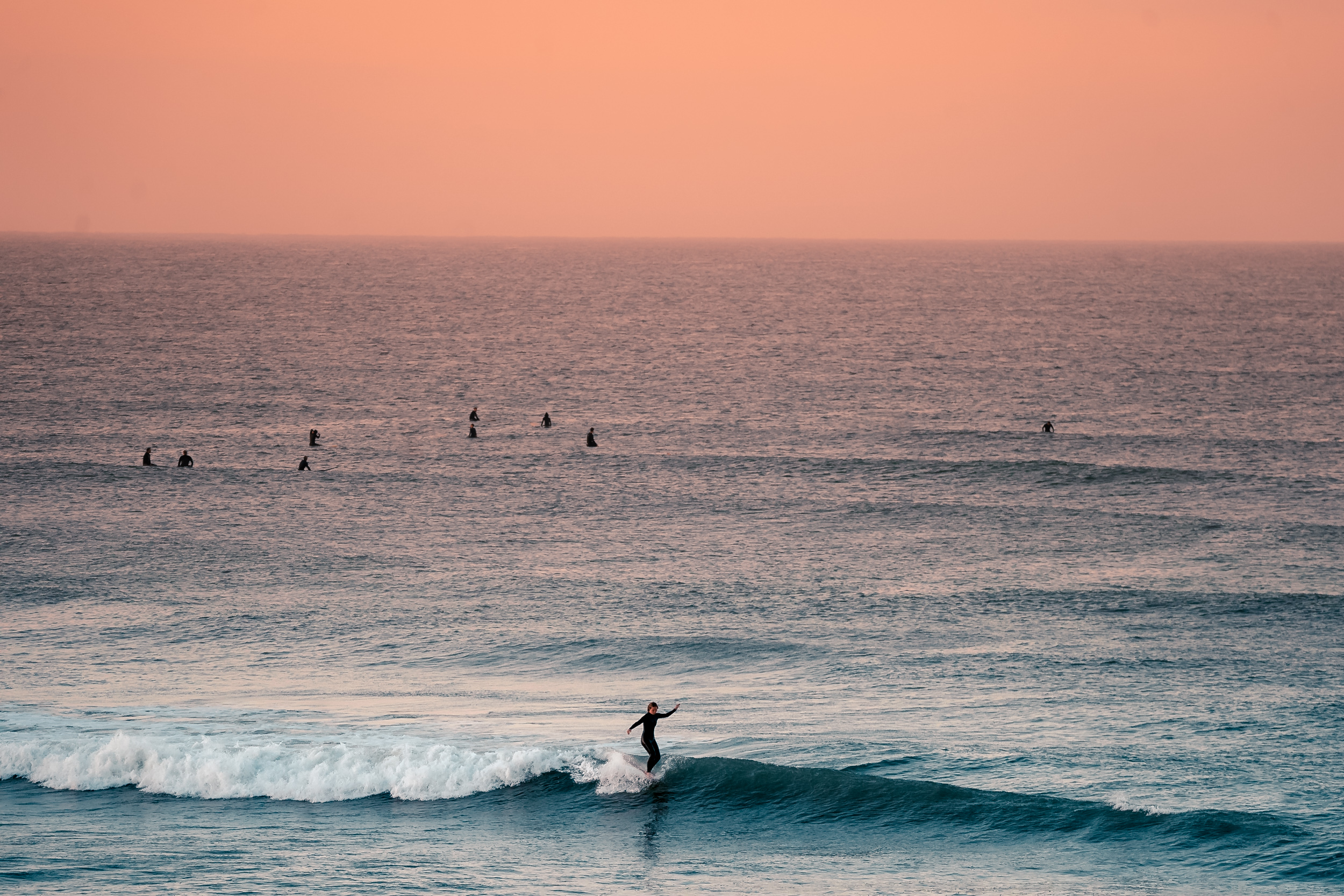 Verschiedene Surfreviere kennenlernen Eine Surferin surft im Weißwasser bei Sonnenuntergang